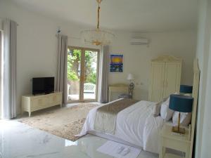 biała sypialnia z łóżkiem i telewizorem w obiekcie Jasmine Bay Hotel & Spa 