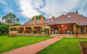 une maison avec une pelouse verte devant elle dans l'établissement Walkersons Hotel & Spa, à Dullstroom