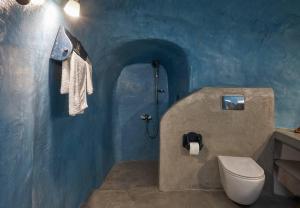 a bathroom with a toilet and a blue wall at Sunlight Cave Agrilia in Thirasia