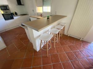 a kitchen with a counter and four stools at Maison a deux pas de Perigueux quartier calme. in Coulounieix-Chamiers