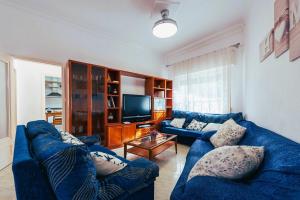 ein Wohnzimmer mit 2 blauen Sofas und einem TV in der Unterkunft Chalet en el Mar Menor (Cartagena) con Piscina Privada y 4 dormitorios in Cartagena