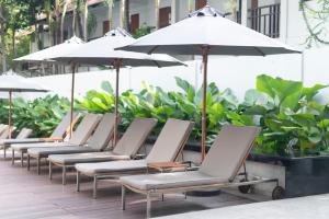 uma fila de espreguiçadeiras com guarda-sóis num pátio em Woodlands Suites Serviced Residences - SHA Extra Plus em Pattaya North