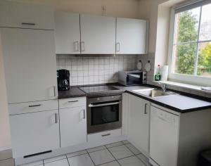 a kitchen with white cabinets and a sink and a microwave at Ferienwohnung Gisela Rohde in Bad Bramstedt