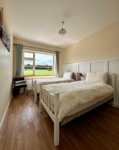 a bedroom with two beds and a window at Breenville Farm House in Tralee