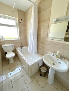 uma casa de banho com uma banheira, um WC e um lavatório. em Breenville Farm House em Tralee