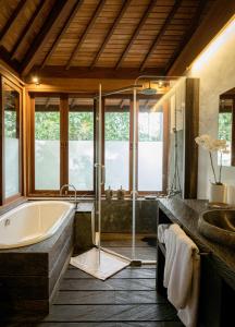 een badkamer met een bad en een wastafel bij De Ubud Villas & Spa in Ubud