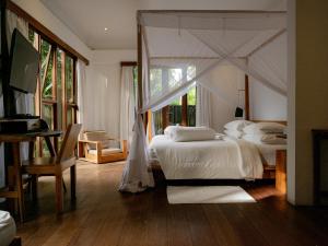 a bedroom with a white bed with a canopy at De Ubud Villas & Spa in Ubud