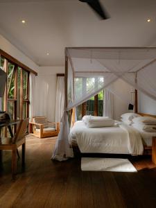 sypialnia z łóżkiem z baldachimem i biurkiem w obiekcie De Ubud Villas & Spa w mieście Ubud