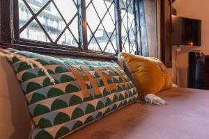 a couch with a pillow next to a window at 15th century tiny character cottage-Henley centre in Henley on Thames