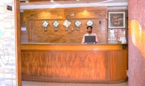 un hombre sentado en un bar con un portátil en Mir Continental Hotel & Restaurant, en Muzaffarabad
