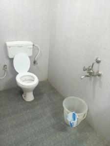 a bathroom with a toilet and a bucket in it at Squirrel Nest Guest House in Mahabalipuram