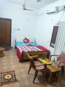 1 Schlafzimmer mit einem Bett, 2 Stühlen und einem Tisch in der Unterkunft Squirrel Nest Guest House in Mahabalipuram