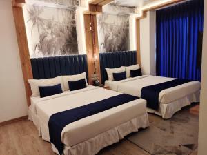 two beds in a hotel room with blue curtains at Grace Cox Smart Hotel in Cox's Bazar