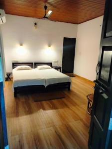 1 dormitorio con 1 cama y suelo de madera en Marari Greenland Homestay, en Mararikulam