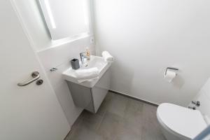 a white bathroom with a sink and a toilet at Hökis-Zimmervermietung 11 mit Küche in Brande-Hörnerkirchen