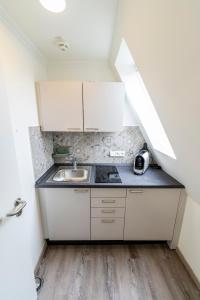 a small kitchen with white cabinets and a sink at Hökis-Zimmervermietung 11 mit Küche in Brande-Hörnerkirchen