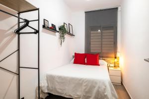 a bedroom with a white bed with red pillows at Beach Apartment, next to the sea in Premiá de Mar