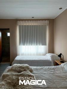 two beds in a hotel room with a window at Hotel Termas Lahuen-Có in Los Molles