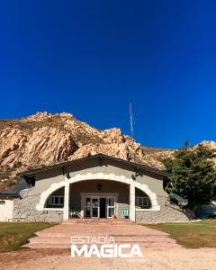 un edificio frente a una montaña rocosa en Hotel Termas Lahuen-Có en Los Molles