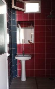 La salle de bains est pourvue de carrelage rouge, d'un lavabo et d'un miroir. dans l'établissement Résidence Marie France MENDY, à Toubab Dialo