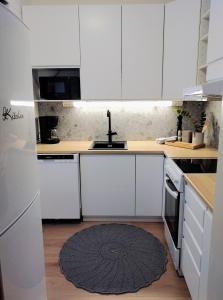 a kitchen with white cabinets and a rug on the floor at Tilava kt Kaksio in Jalasjärvi