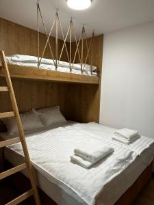 a bunk bed with white sheets and towels on it at Apartment Aurora in Bjelašnica