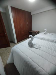 two swans sitting on a bed in a bedroom at Ataraxia Light House in Cusco