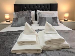 uma cama com toalhas brancas com dois candeeiros em THROSTLES NEST APARTMENTS em Manchester