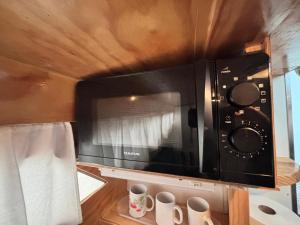 a microwave above a kitchen counter with two cups at Wonderful boat for families and friends in Barcelona