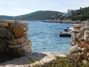 a stone wall next to a body of water at Holiday House Rivi in Milna