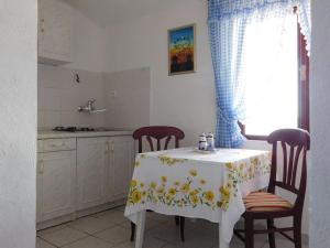 a kitchen with a table and two chairs and a table and a window at Holiday House Rivi in Milna