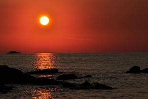 a sunset over the ocean with rocks in the water at Holiday House Rivi in Milna