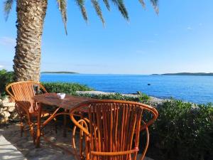 a wooden table and chairs next to a tree and the ocean at Holiday House Rivi in Milna