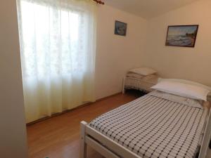 a small bedroom with a bed and a window at Holiday House Rivi in Milna