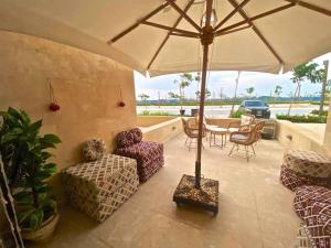 um pátio com cadeiras, um guarda-sol e uma mesa em Glamorous 2BR/ Free Beach & Pool Access @ Mangroovy, El Gouna em Hurghada