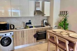 a kitchen with a table and a sink and a dishwasher at Glamorous 2BR/ Free Beach & Pool Access @ Mangroovy, El Gouna in Hurghada