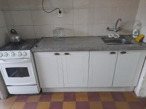 a kitchen with white cabinets and a sink and a stove at Terrazas del Palomar in Salto
