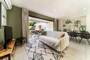 a living room with a couch and a television at Magnifique villa avec jacuzzi Proximité mer in Saint-Joseph