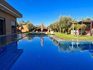 uma piscina com vista para uma casa e seu reflexo na água em agafay villa em Marrakech