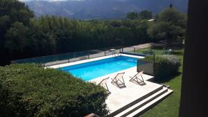a swimming pool with four chairs at La Soñada Cabañas & Spa in Merlo