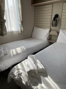 two beds in a room with towels on them at Luxury Holiday Home Sleeps 6 Pet Friendly in St Austell