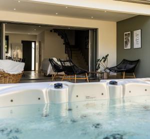 uma banheira de hidromassagem num quarto com cadeiras e uma sala de estar em Magnifique villa avec jacuzzi Proximité mer em Saint-Joseph