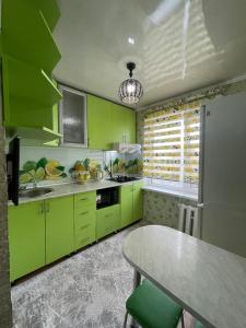Una cocina con gabinetes de color verde lima y una mesa. en 2-х комнатная квартира в 5 микрорайоне, en Bishkek