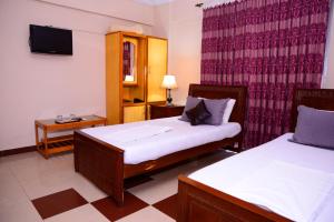 Habitación de hotel con 2 camas y TV en Mir Continental Hotel & Restaurant, en Muzaffarabad