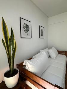 a bedroom with a white bed and a potted plant at Amplio Departamento en Zona Gastronómica a una cuadra de la Playa in Mar del Plata