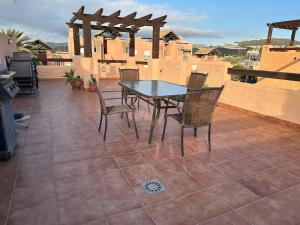 een patio met een tafel en stoelen op een dak bij Casares del Sol penthouse with private roof terrace 80m2 in Bahia de Casares