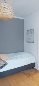 Cama en habitación con pared blanca en Apartment Lintu, en Mikkeli