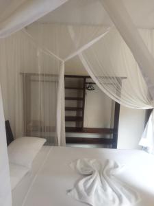 a bedroom with a bed with white sheets and a mirror at Casa da Drica Trancoso in Trancoso