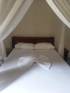 a white bed with a bow tie on it at Casa da Drica Trancoso in Trancoso