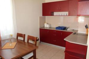 PM Services Royal Plaza Apartments في بوروفتس: مطبخ صغير مع دواليب حمراء وطاولة خشبية